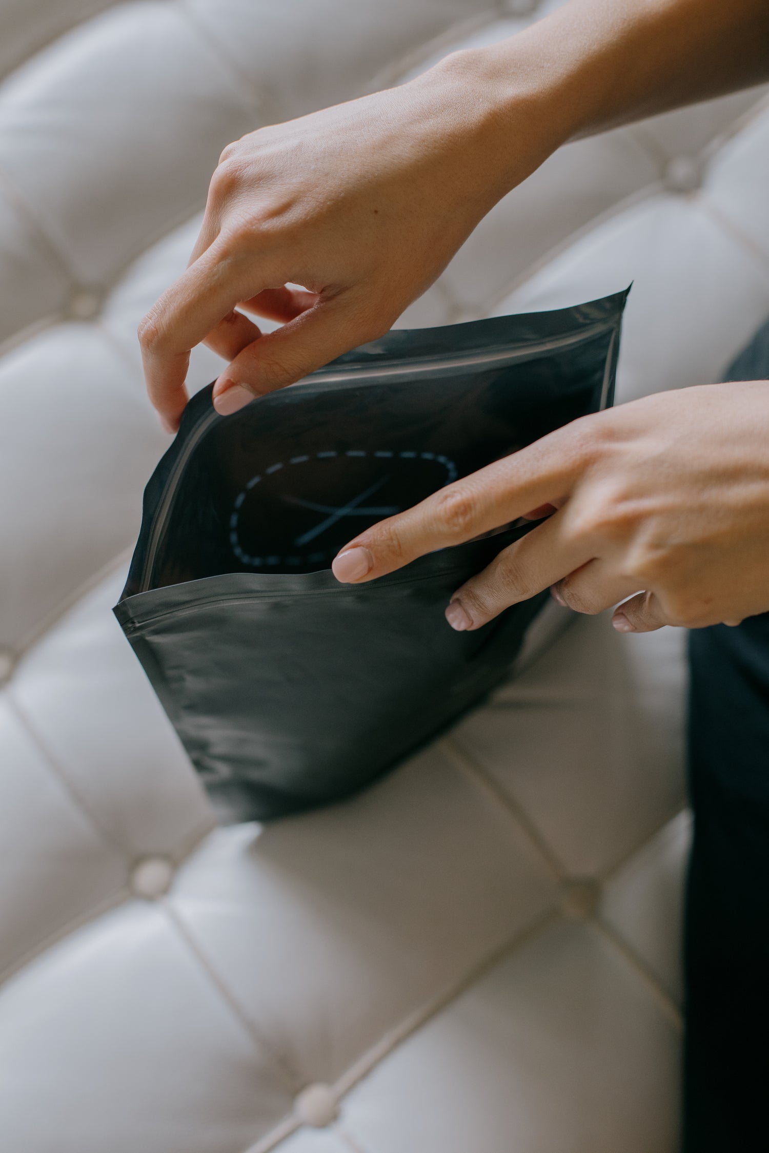 hands-hold-open-a-black-plastic-envelope-on-couch - Simply Conveniently